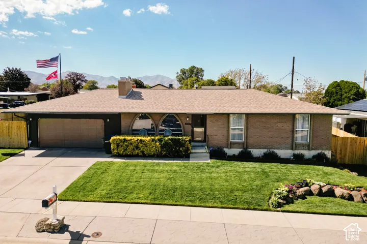 Brick exterior with arched windows, attached garage, and a well-maintained front lawn