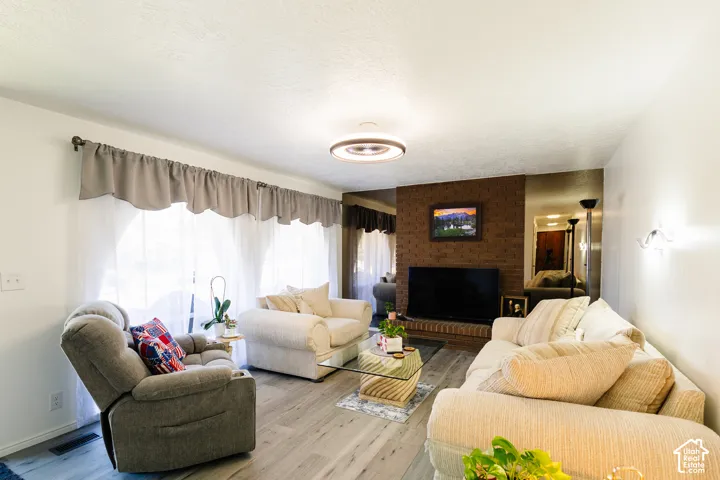 Light wood-finish flooring, brick accent wall, and recessed ceiling lighting