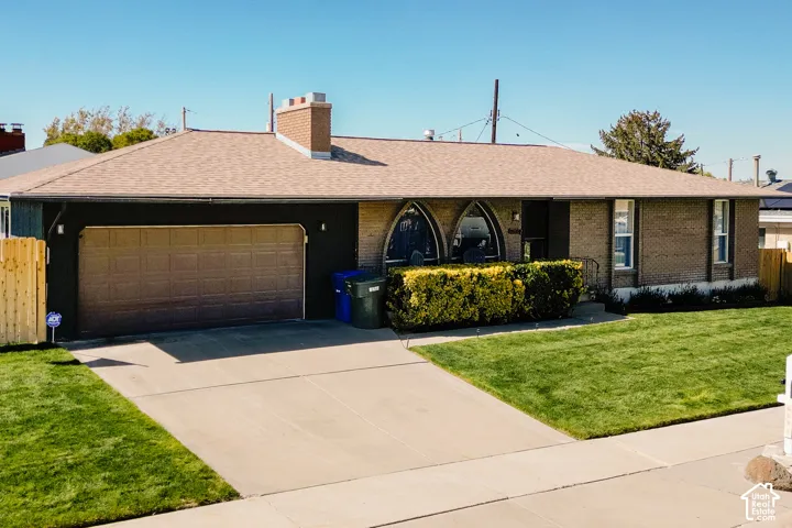 Brick exterior with arched windows, attached garage, concrete driveway, and a fenced side yard