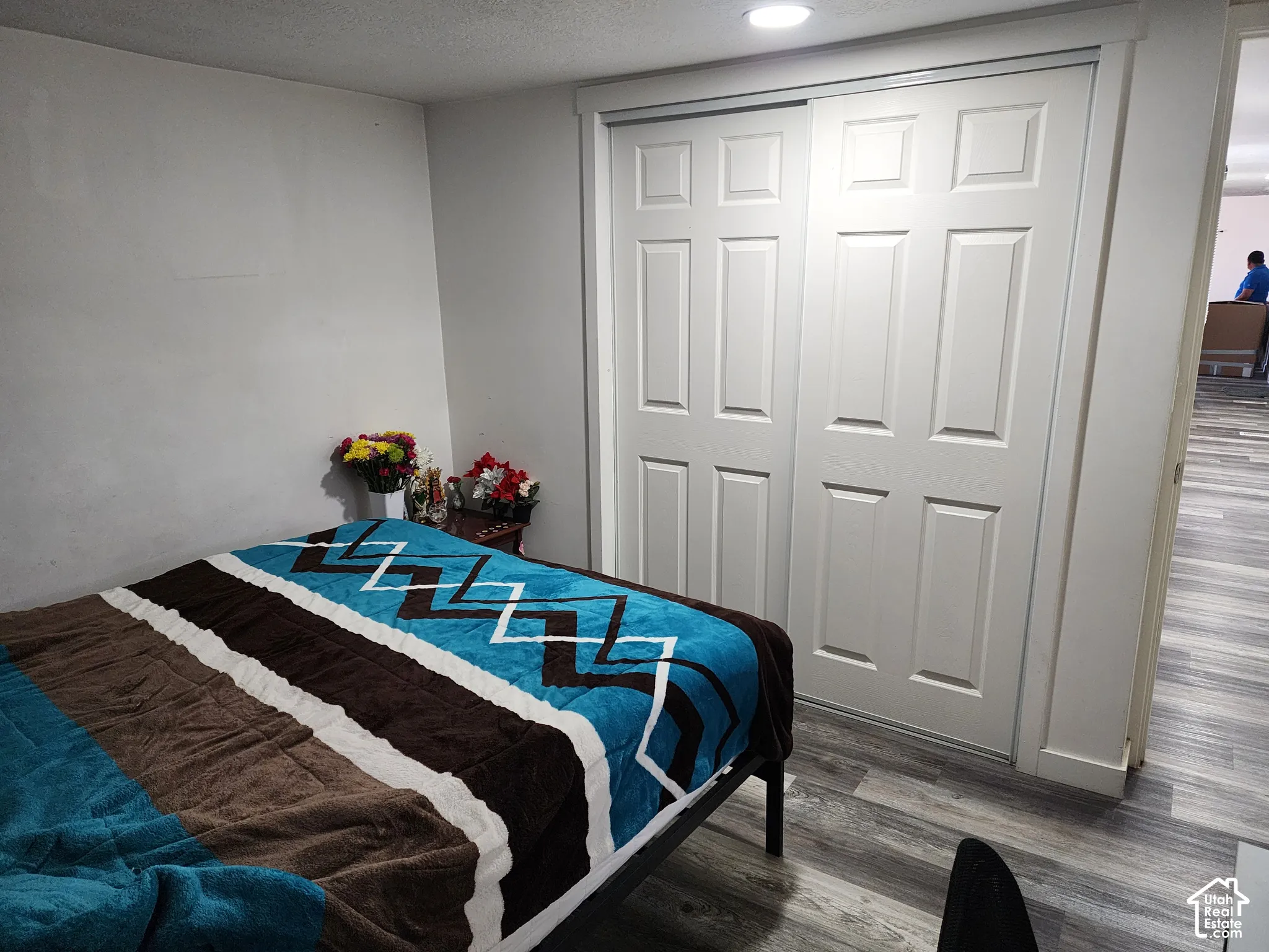 White paneled closet doors, recessed ceiling lighting, and wood-finish flooring