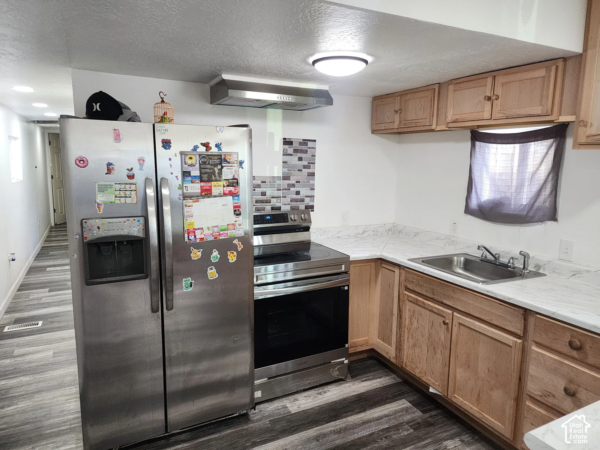 Wood-finish flooring with light-toned cabinetry, a stainless steel sink, and white countertops