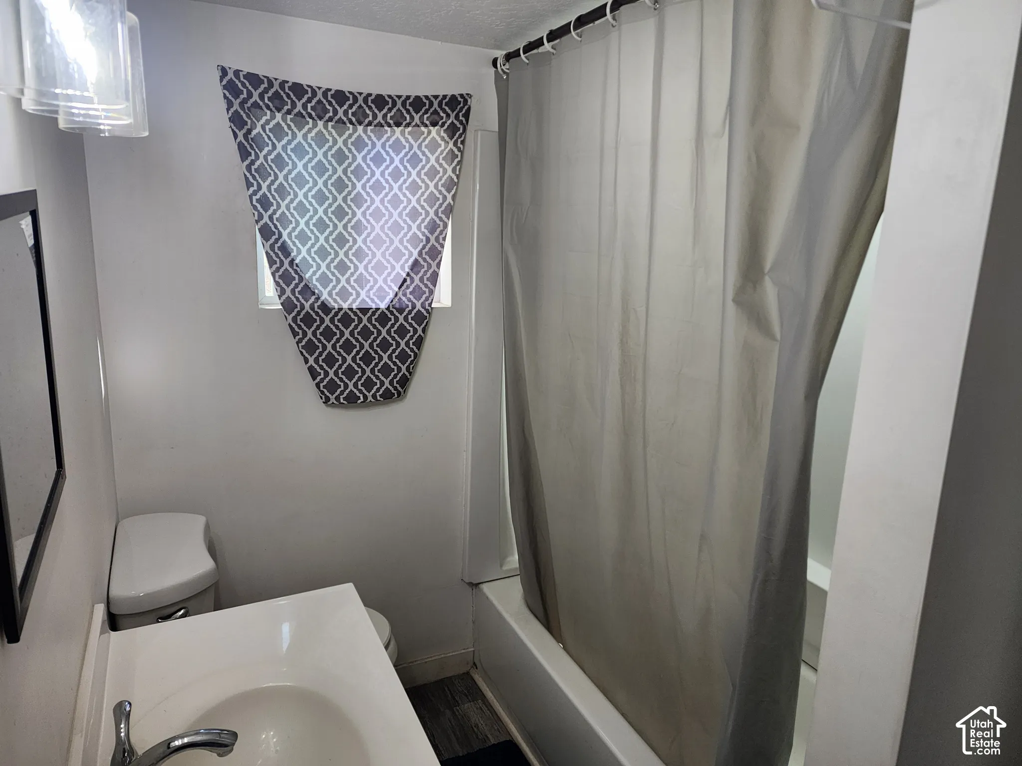 Bathroom featuring a white vanity with integrated sink, chrome faucet, white toilet, and tub with shower