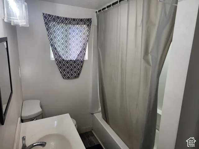 Bathroom featuring a white vanity with integrated sink, chrome faucet, white toilet, and tub with shower