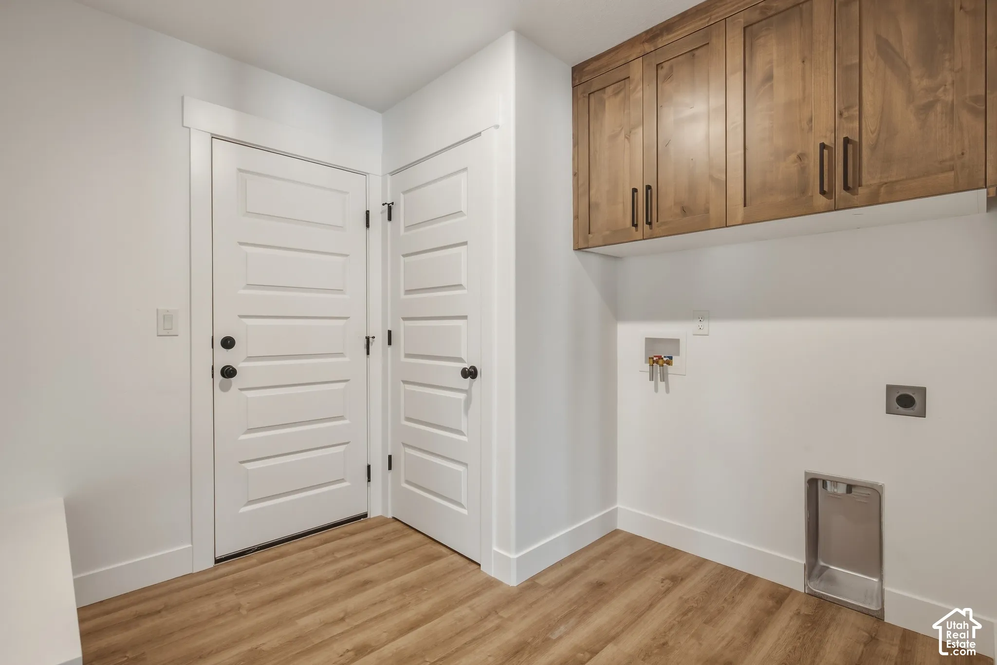 Wood-finish flooring, white paneled doors, and wood cabinetry with matte black hardware