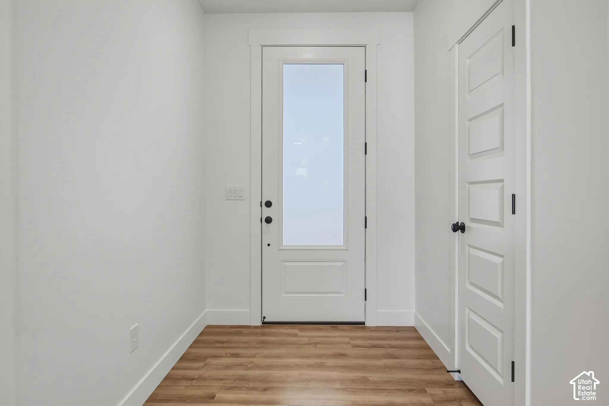Wood-finish flooring, white paneled doors, and white walls