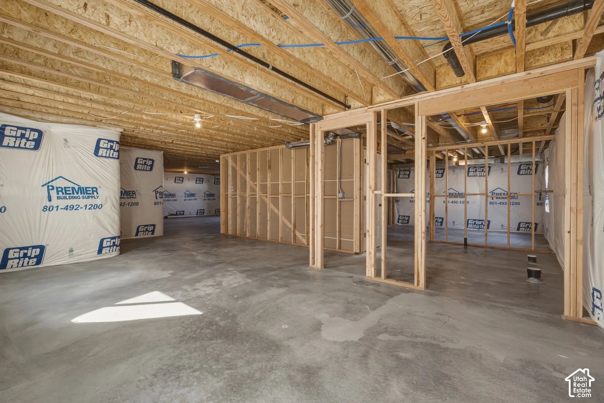 Unfinished basement with exposed wood framing, concrete flooring, and visible ductwork