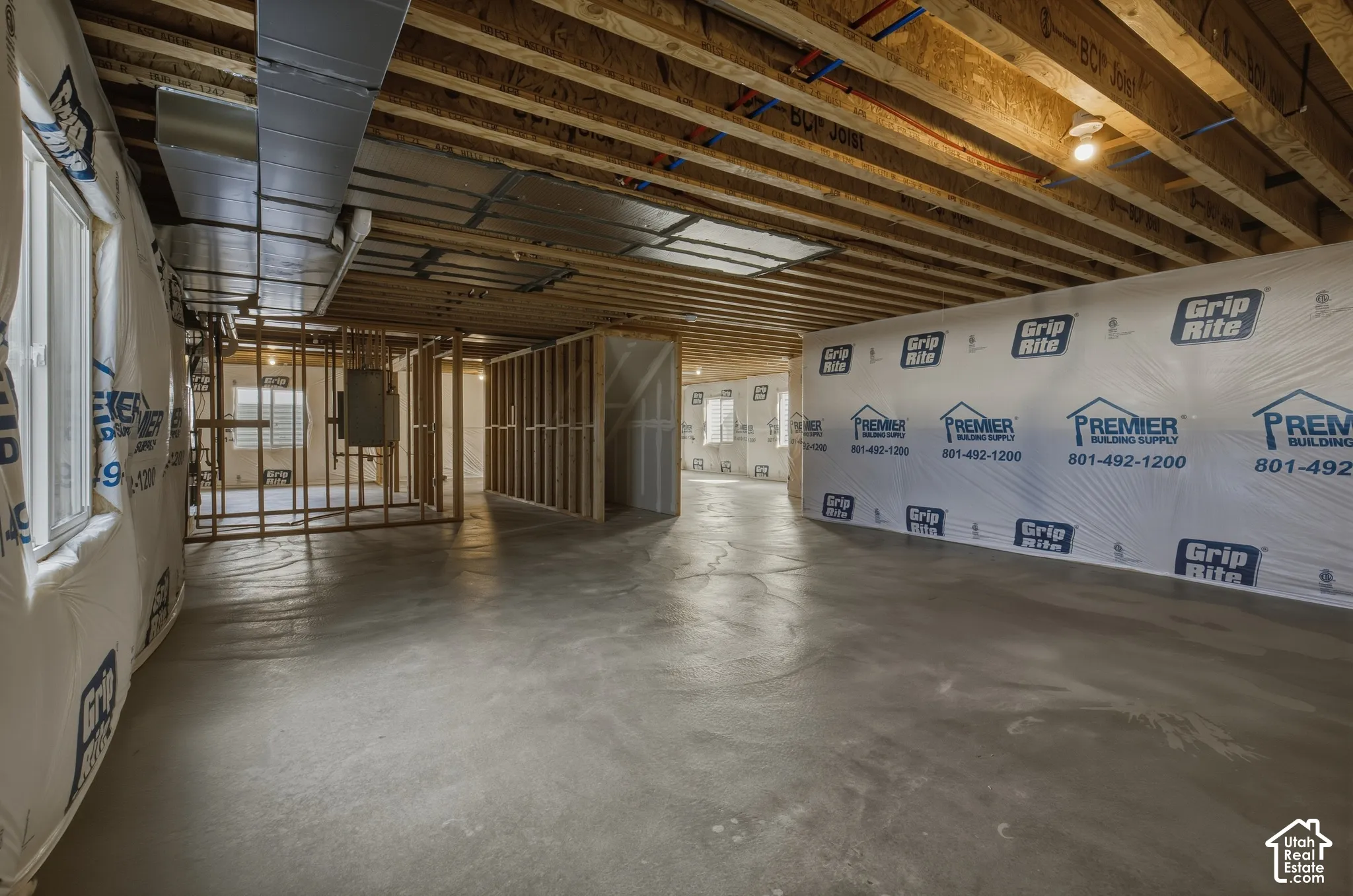 Unfinished basement with concrete flooring, exposed wood joists, and visible structural framing