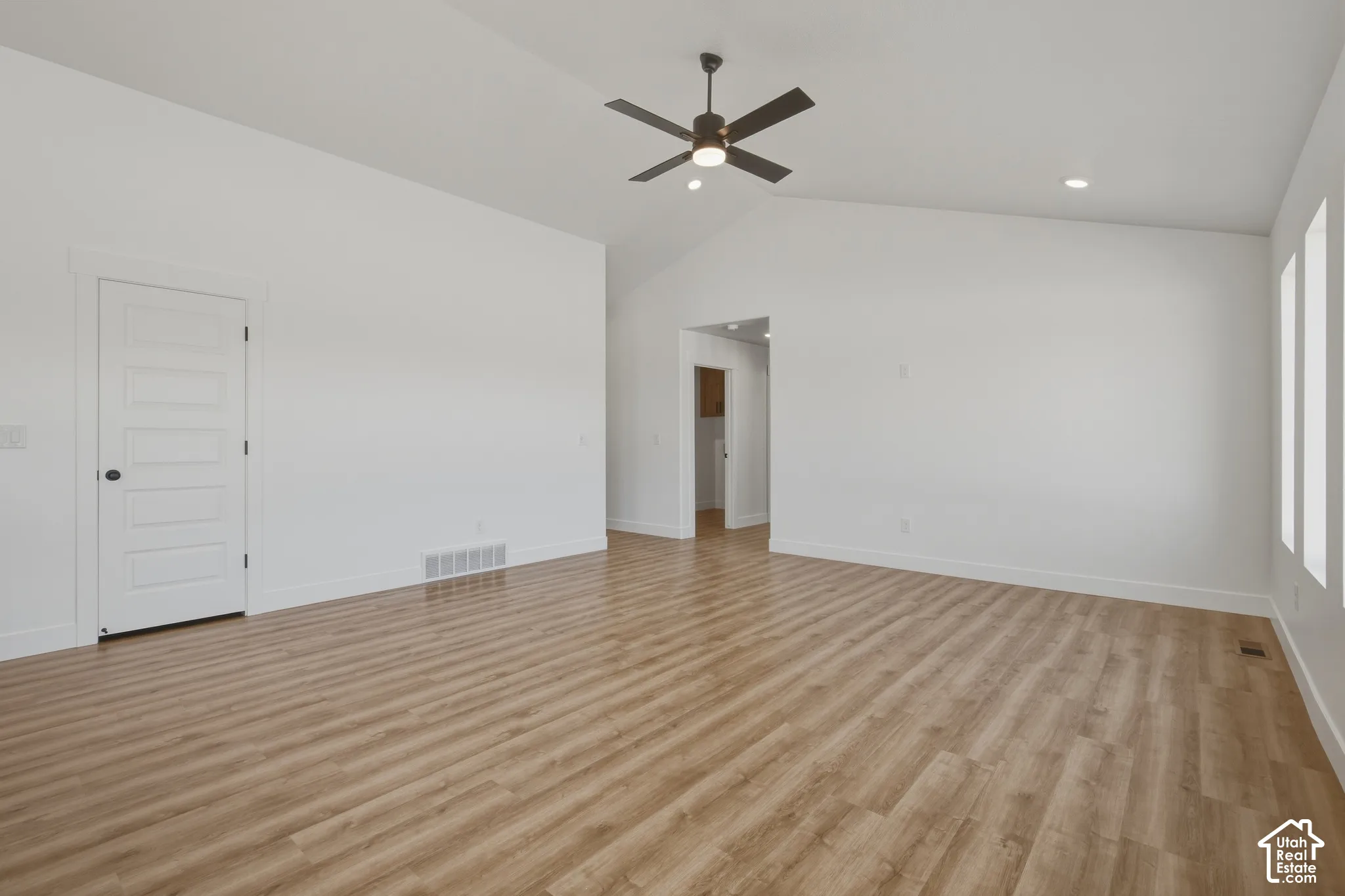 Vaulted ceiling with a ceiling fan, wood-finish flooring, recessed lighting, and white trim