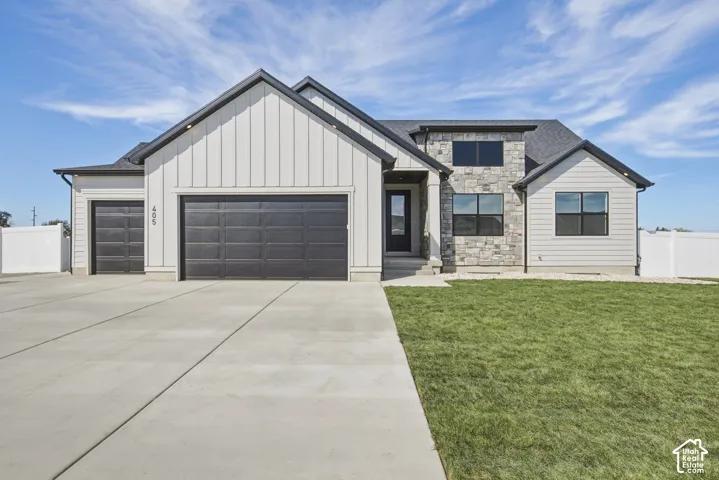 Modern exterior featuring vertical siding, stone accents, black-framed windows, a multi-car garage, and a concrete driveway