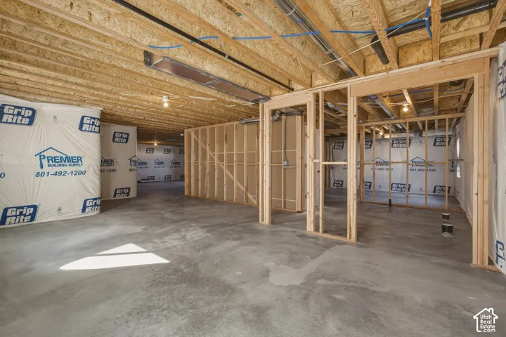 Unfinished basement with exposed wood framing, concrete flooring, and visible ductwork