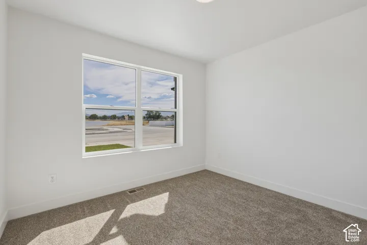 Recessed ceiling lighting, white walls, broad window, and gray carpeting