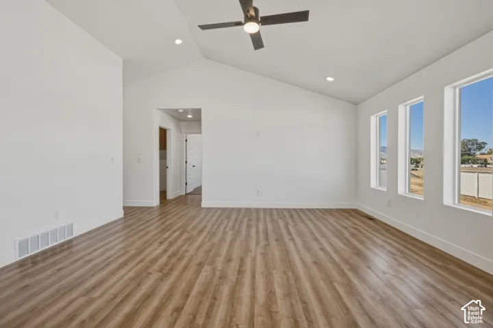 Vaulted ceiling with a contemporary ceiling fan, recessed lighting, and wood-finish flooring