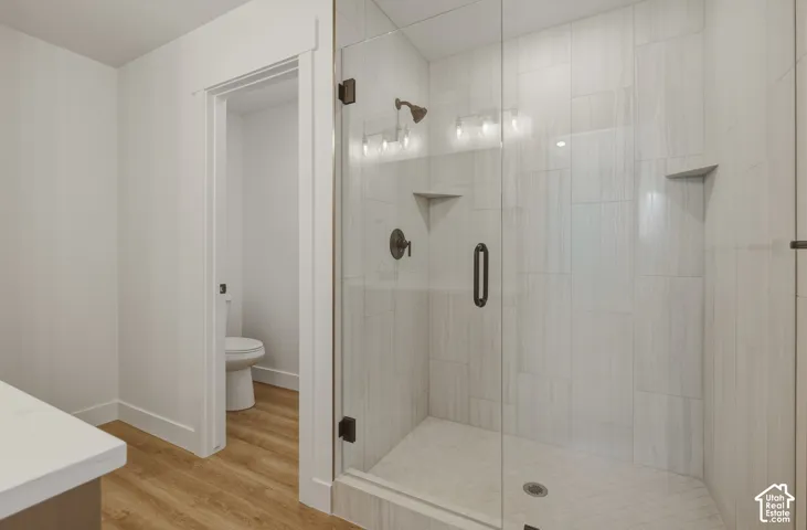 Glass-enclosed shower with vertical-set tile surround, dual built-in shower shelves, and matte black fixtures