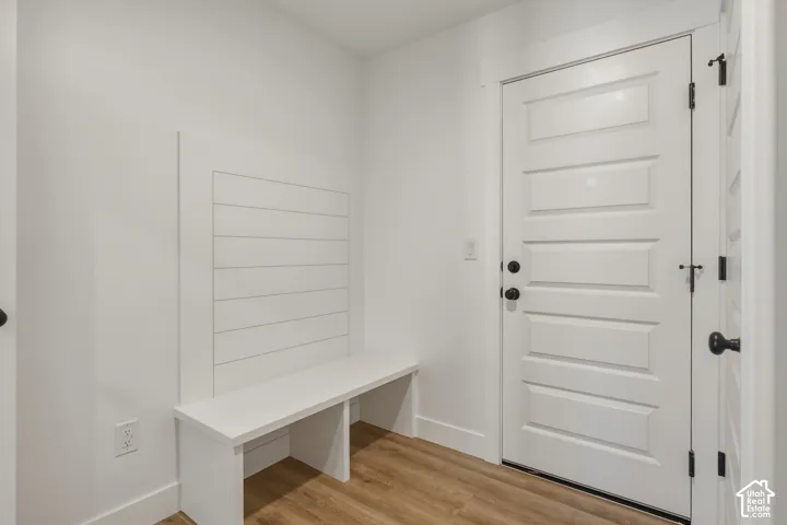 Built-in bench with shiplap-style wall paneling, five-panel interior door, and wood-finish flooring