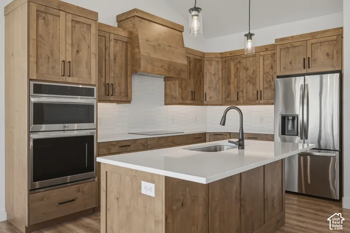 Kitchen featuring wood cabinetry, stainless steel appliances, white subway tile backsplash, white countertops, and wood-finish flooring