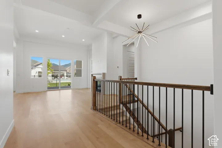 Hardwood flooring, contemporary chandelier, sliding glass doors, coffered ceiling, and wrought iron balusters