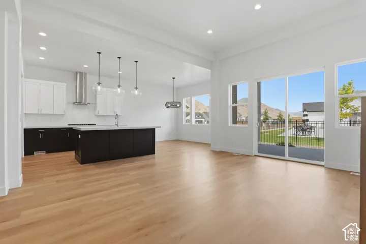 Open-concept living space with wood-finish flooring, a contemporary kitchen island, stainless steel appliances, and large sliding glass doors leading to the outdoor patio