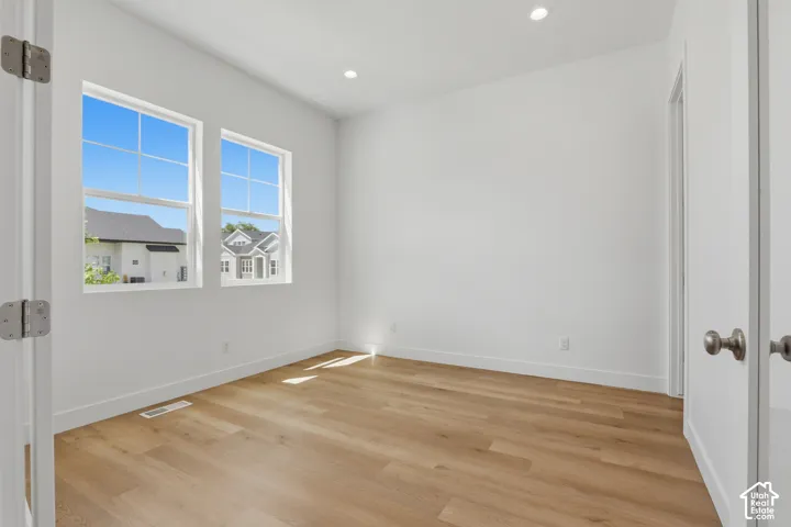 Bright interior with wood-finish flooring, recessed lighting, and white walls