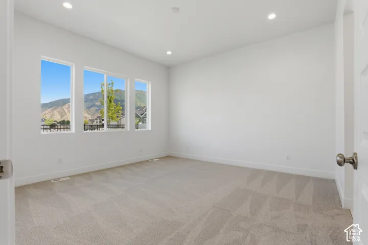 Recessed lighting illuminates neutral carpeting and white walls