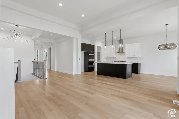 Open-concept living space featuring light wood-finish flooring, recessed lighting, and a modern kitchen