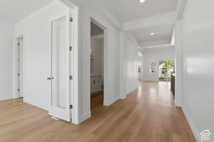 Light wood-finish flooring, white walls, recessed lighting, and a white vanity with a rectangular sink