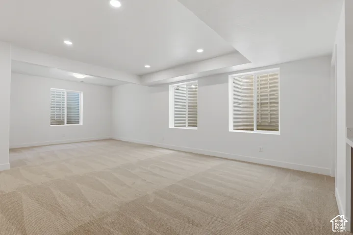 Spacious room featuring gleaming wood-finish flooring, recessed ceiling lighting, and an abundance of natural light from multiple shuttered windows
