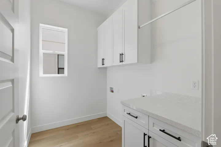 Bright utility space featuring white cabinetry, light wood-finish flooring, a white countertop, and a window