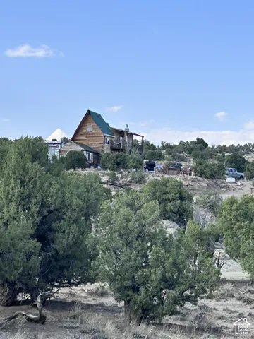 Log cabin exterior featuring a green gable roof, wood siding, and an elevated deck