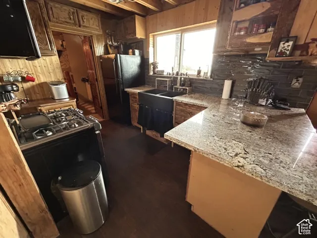 Wood-paneled kitchen featuring an integrated gas range, dual-basin sink, and light-toned countertops