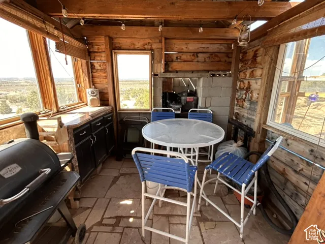 Wood-paneled interior with multiple windows, exposed beam ceiling, stone-finish flooring, and built-in cabinetry with a countertop
