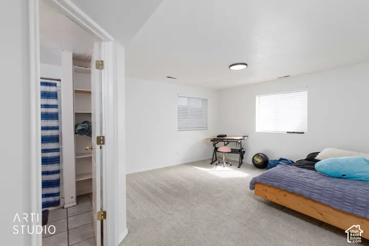 Carpeted room with multiple windows, a ceiling-mounted light fixture, and an adjacent tiled area with built-in shelving