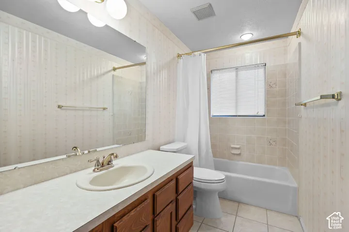 Wood-finish vanity with an integrated sink, broad wall mirror, and overhead vanity lighting