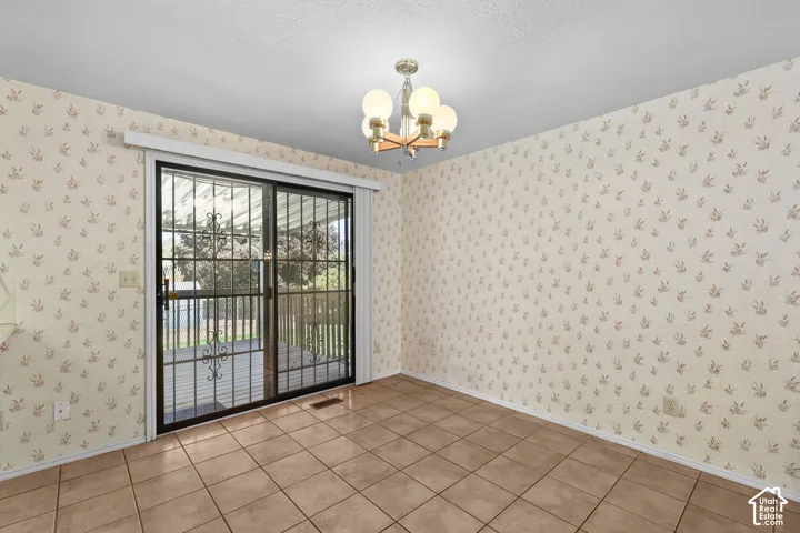 Sliding glass door with security grate, tile flooring, and a ceiling-mounted light fixture