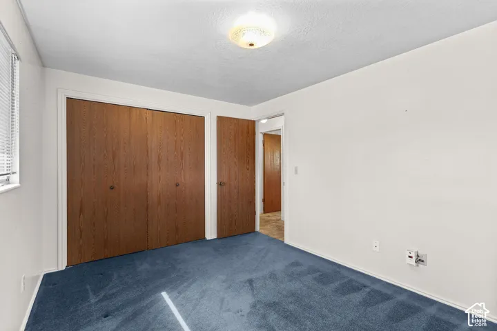 Bedroom featuring blue carpeting, white walls, and wood-finish closet doors