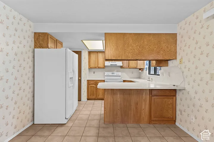 Kitchen featuring wood-finish cabinetry, light countertops, and tile flooring
