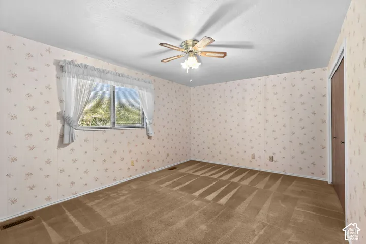 Recessed window, patterned wallpaper, ceiling fan, and carpeted flooring