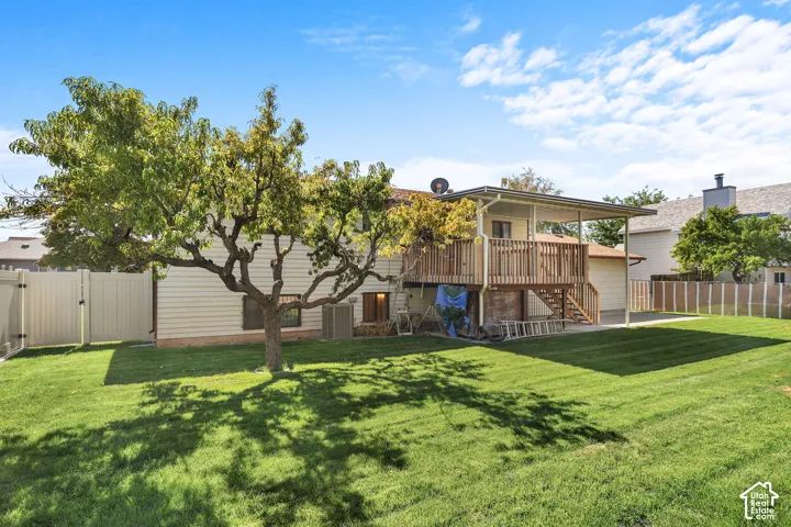 Expansive backyard featuring a manicured lawn, mature tree, and a two-story wood deck with a covered lower level