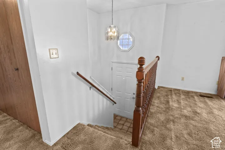 Stairwell featuring a wood-finish banister, white paneled door, and an octagonal window