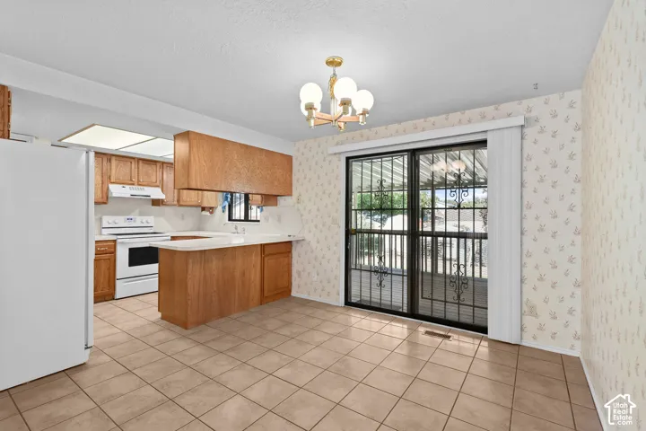 Tile flooring, wood-finish cabinetry, white appliances, built-in breakfast bar, and sliding glass door
