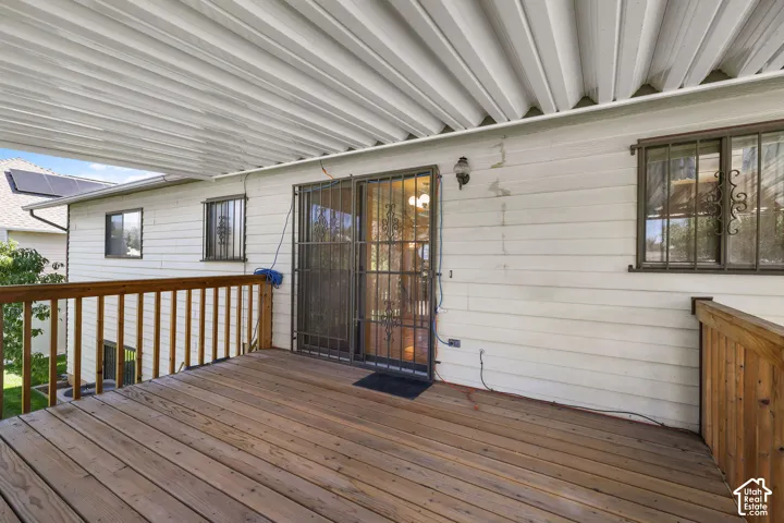 Expansive wood deck with a full wood railing, covered by a corrugated metal patio roof