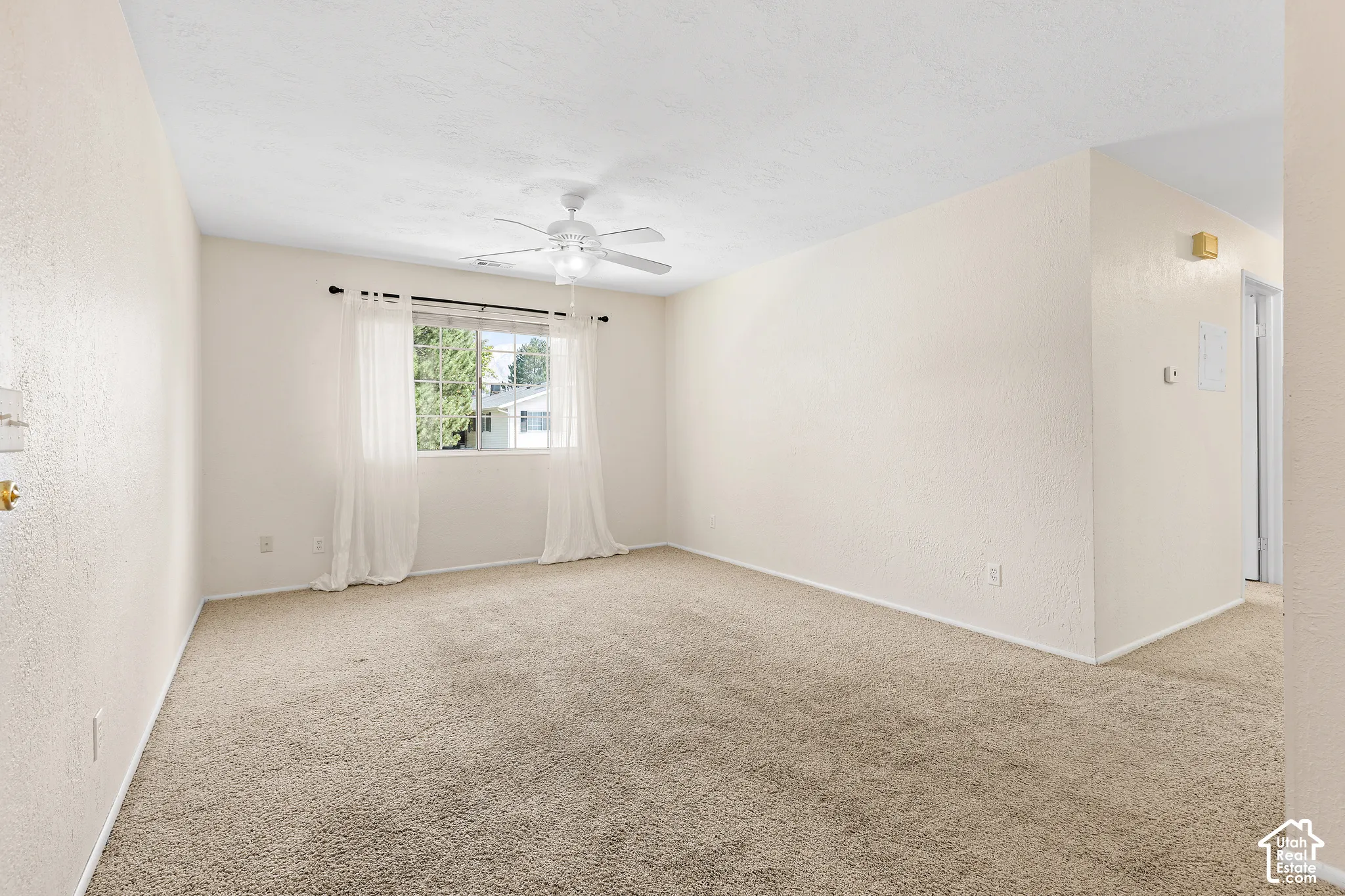 Carpeted room featuring a ceiling fan, a window, and textured walls