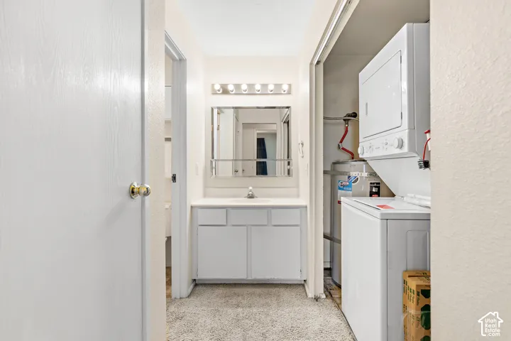 Bathroom vanity with a single sink and wall-mounted light fixture, adjacent to a stacked washer and dryer unit