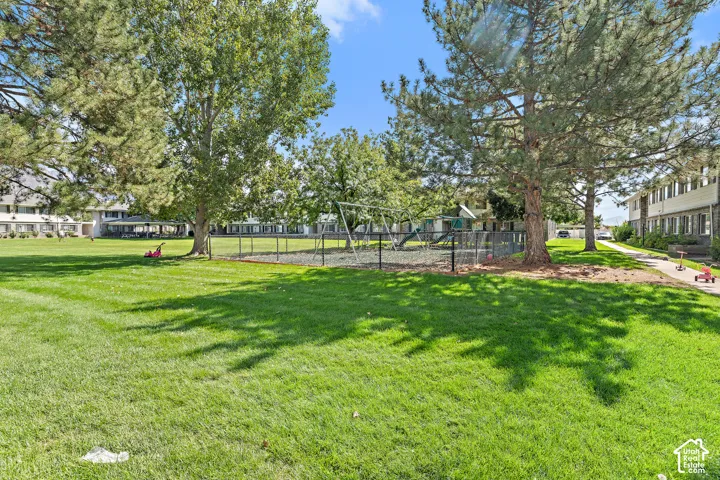 Expansive green space featuring a playground, mature trees, and paved pathways