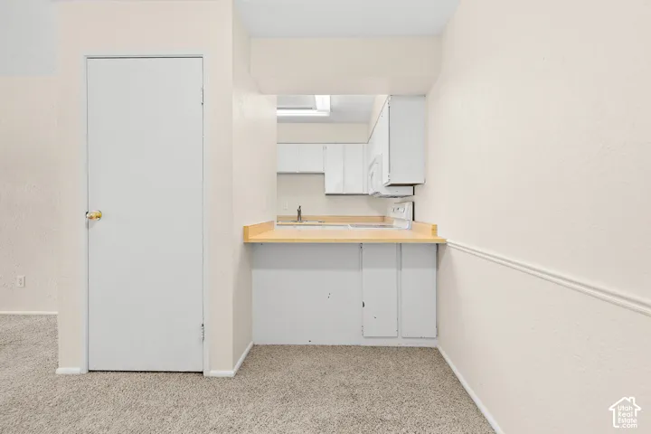 Kitchen pass-through with wood-finish countertop, stainless steel sink, and white cabinetry