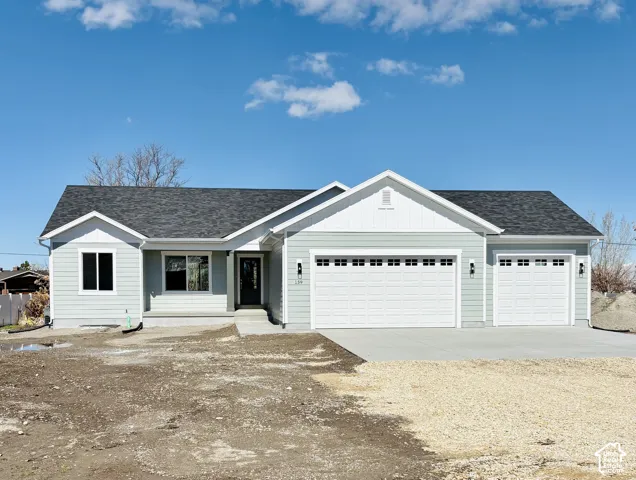 Light blue siding exterior with white trim, dark asphalt shingle roof, two-car garage, single-car garage, and concrete driveway
