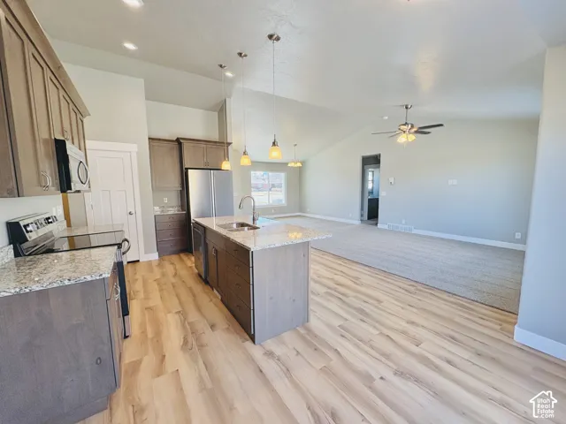 Kitchen featuring wood-finish flooring, granite countertops, an island with a sink, and stainless steel appliances