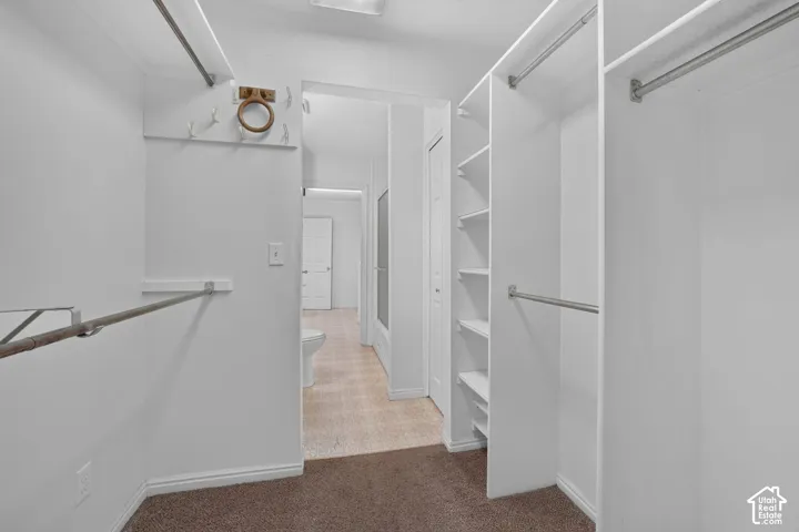 Primary Walk-in closet featuring built-in shelving and multiple hanging rods
