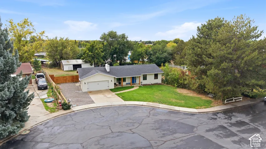 Single-story property featuring an attached garage, a gravel parking area, and a separate outbuilding