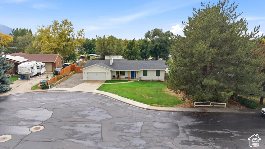 Single-story residence with an attached two-car garage, featuring a light-colored exterior and a prominent front lawn