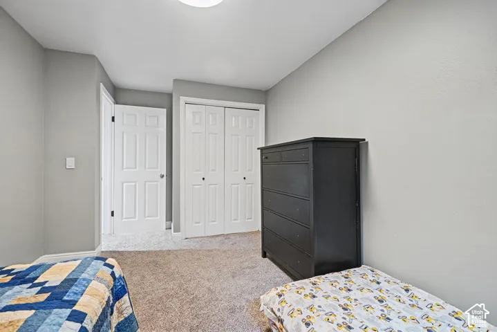 Light gray wall finish, neutral tone carpeting, white bi-fold closet doors, white paneled interior door, and a flush mount ceiling light